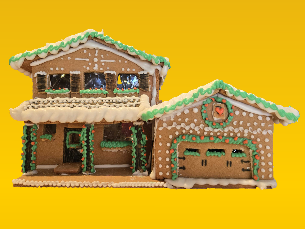 A detached single family home made of gingerbread with an intricate icing details in white and green.